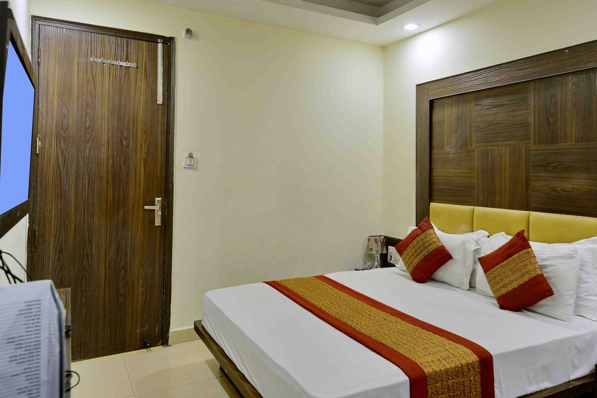 A hotel room with a bed, a television, and a wooden door.