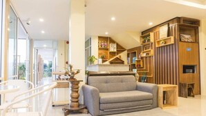 Un salon moderne avec un canapé gris, des étagères en bois et un coin repas avec des chaises blanches.