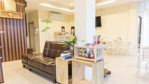 Un salon moderne avec un canapé en cuir, une table basse en bois et une chaise blanche. On y trouve une petite étagère en bois sur laquelle sont disposés divers objets.