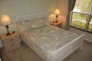 Een slaapkamer met een bed, twee nachtkastjes, een raam en gordijnen.