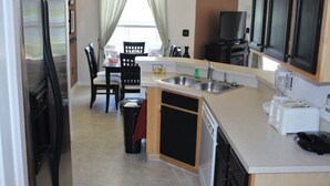 Eine kompakte Küche mit Kühlschrank, Herd, Spüle und einer kleinen Essecke mit Stühlen und Tisch.