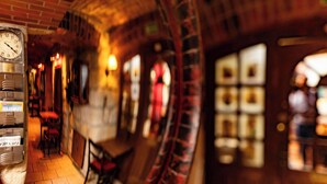 A narrow corridor with a clock, red chairs, and a tiled floor. - Hotel Ambasada Bolesławiec (Boleslawiec)