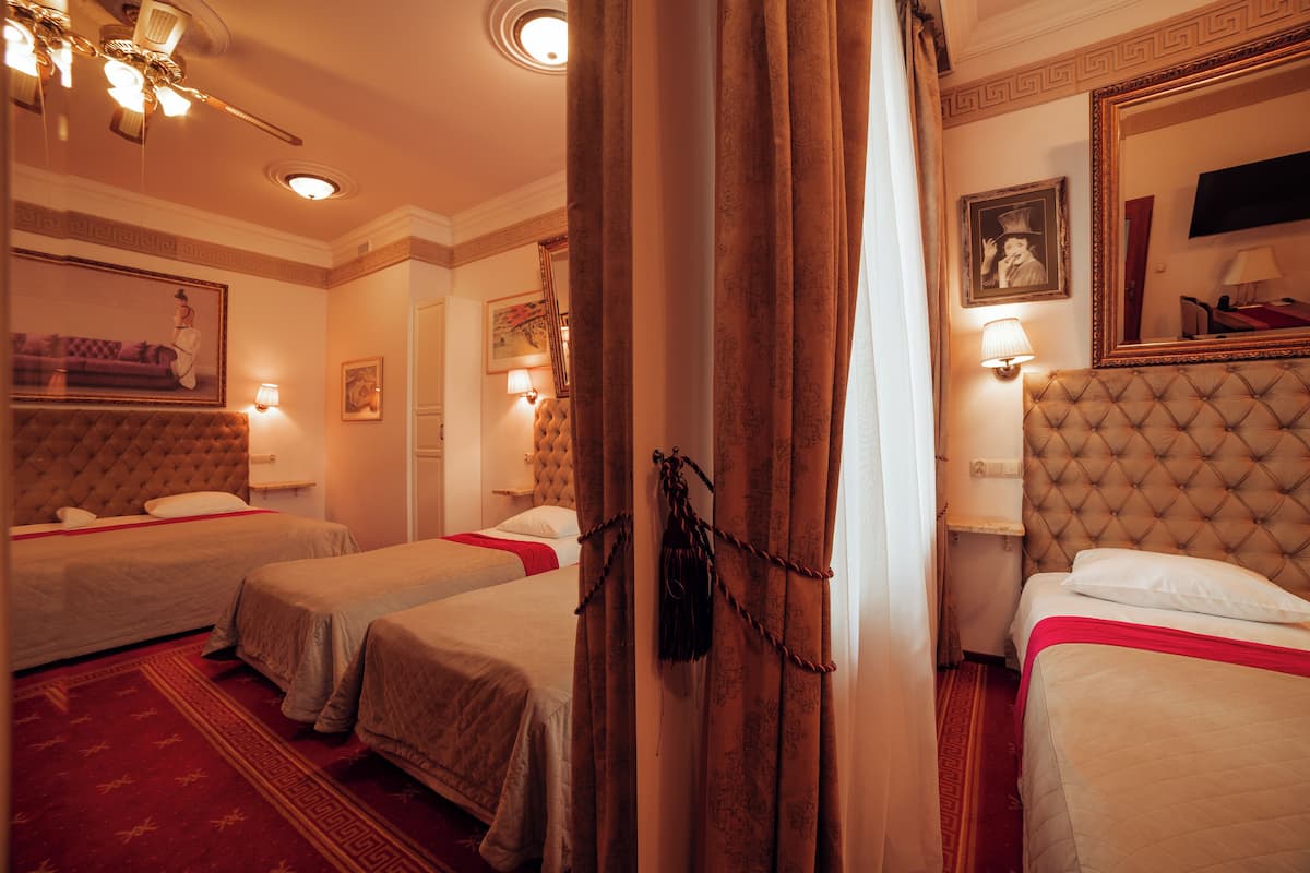 Une chambre d’hôtel avec deux lits, un grand miroir et une moquette rouge.