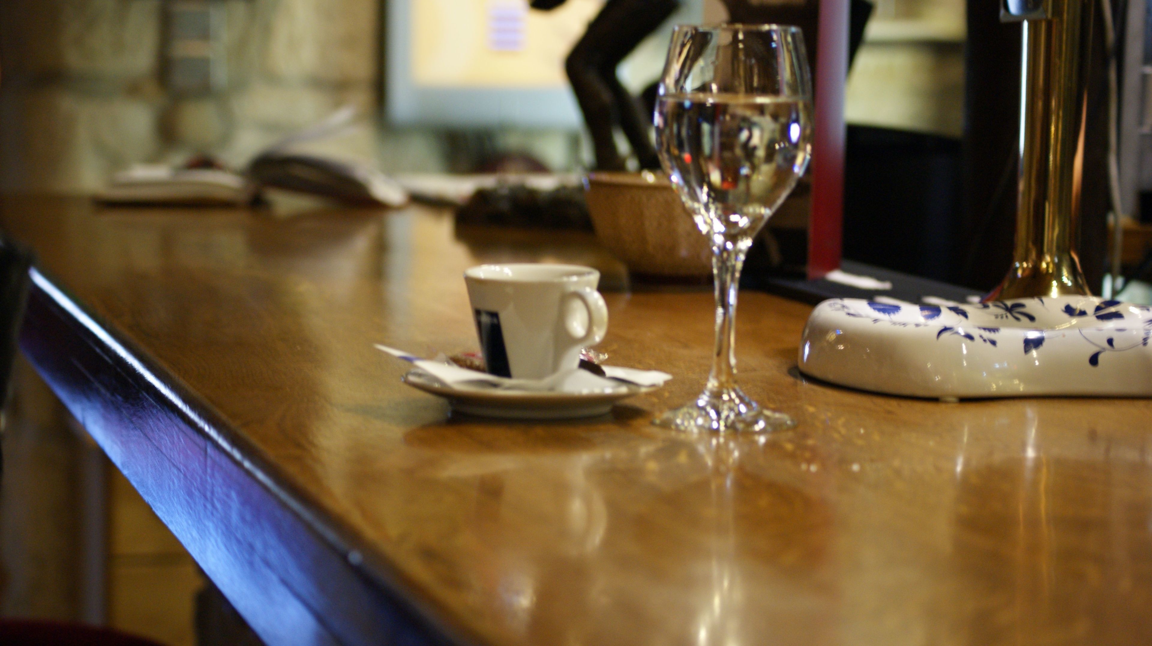 A bar area with a cup and a wine glass on the counter.