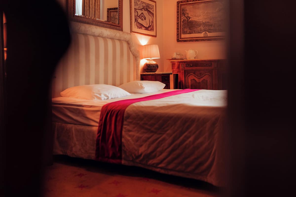 Une chambre d’hôtel avec un lit, une table de chevet, une lampe et une commode.