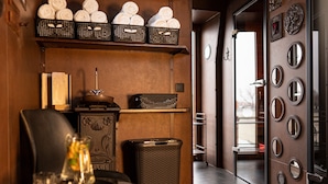 A modern interior with a Buddha statue, shelves with towels, a clock, and a door with circular mirrors. - Hotel Ambasada Bolesławiec (Boleslawiec)