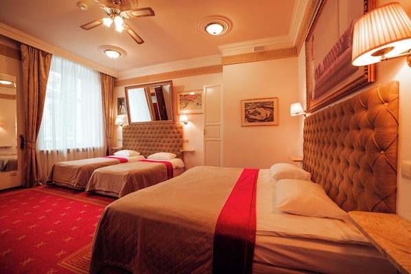 Ein Hotelzimmer mit zwei Betten, einem roten Teppich, einem Deckenventilator und einem großen Spiegel.