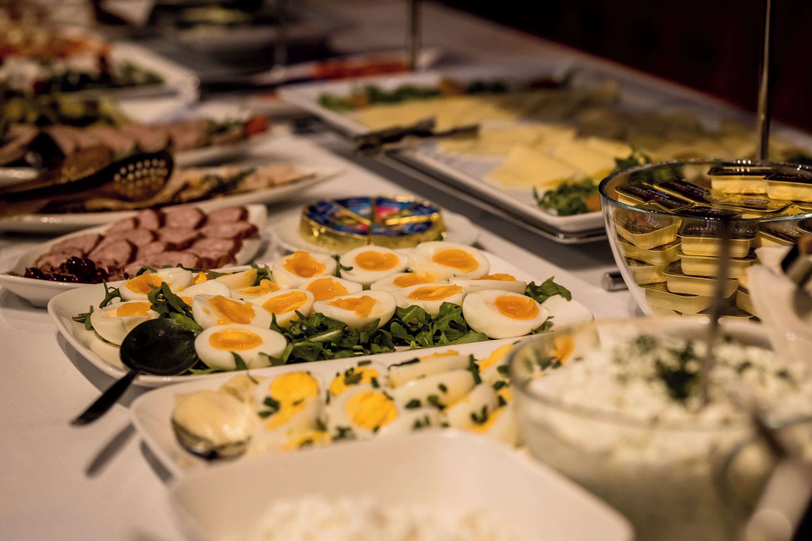 Una mesa de buffet con diversos platos, incluyendo huevos, ensaladas y carnes.