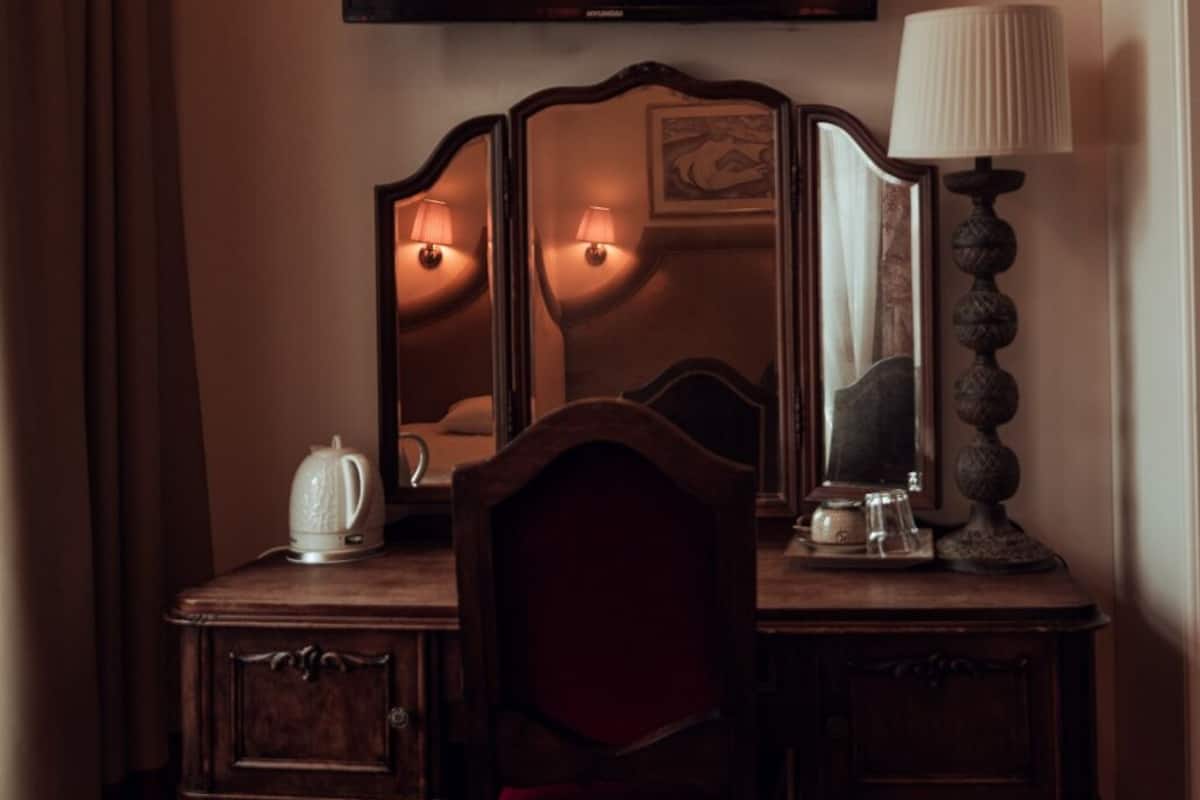 Une chambre d’hôtel équipée d’un bureau en bois, d’une chaise, d’un téléviseur à écran plat et d’une lampe.