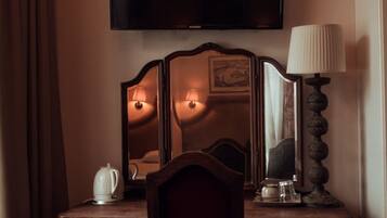 A hotel room with a wooden desk, a chair, a flat-screen TV, and a lamp.