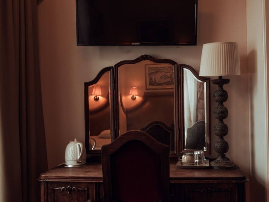 A hotel room with a wooden desk, a chair, a flat-screen TV, and a lamp.