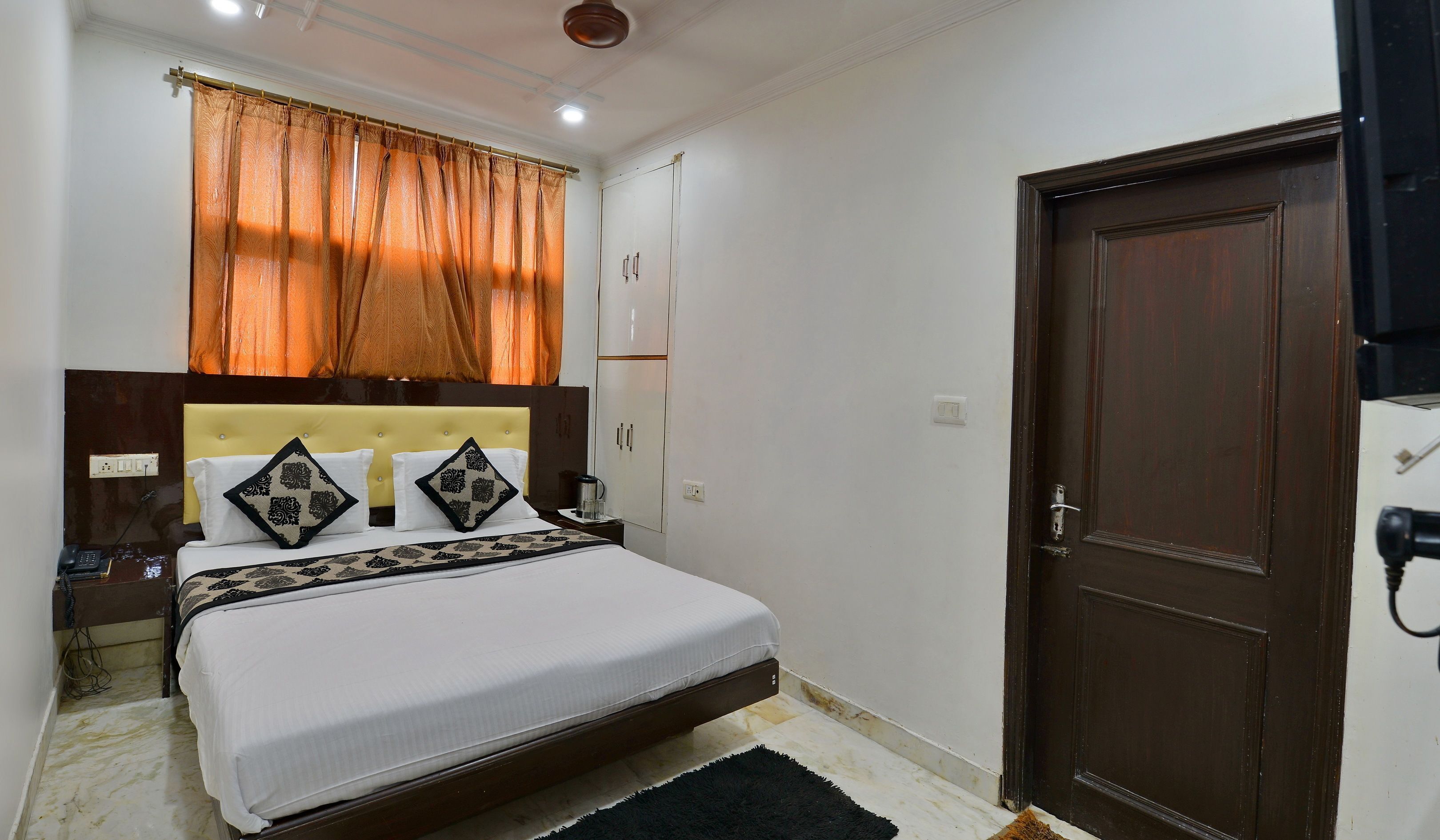A bedroom with a bed, nightstand, wardrobe, and a door.