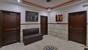 A lobby with marble flooring, a bench, and two wooden doors marked with numbers 102 and 104. - PG International (New Delhi)