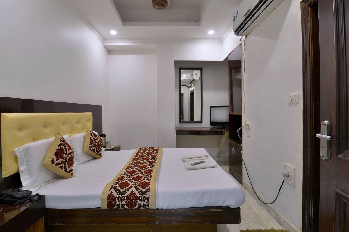 A hotel room with a bed, bedside table, and a desk with a chair.