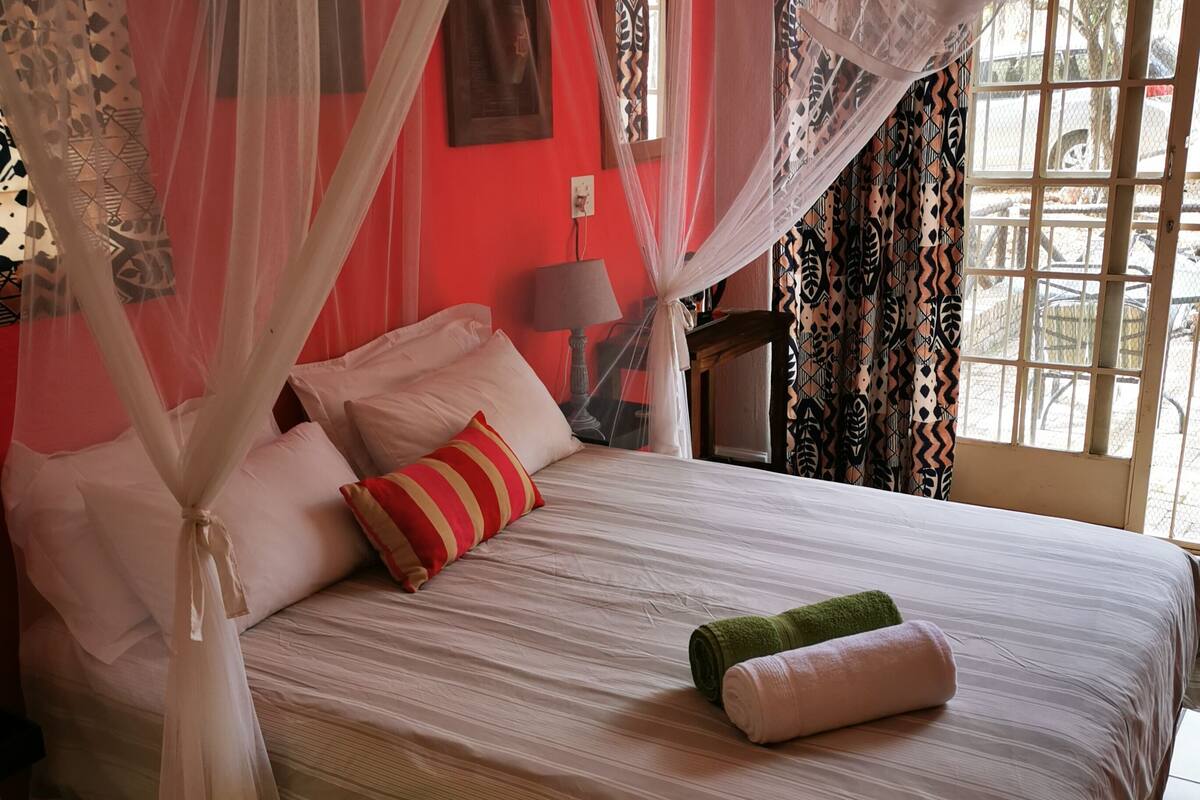 A bed with a canopy, pillows, and a green and pink towel.