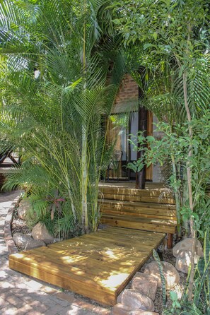 A wooden deck leading to a brick building surrounded by lush greenery. - HomeBase Kruger - Hostel (Nkomazi)
