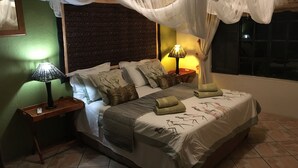 Cama bem arrumada com dossel, duas luminárias laterais e parede estampada.