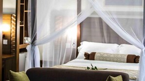 A hotel room with a bed, a nightstand, and a bookshelf. - Hotel  Victoria (Blantyre)