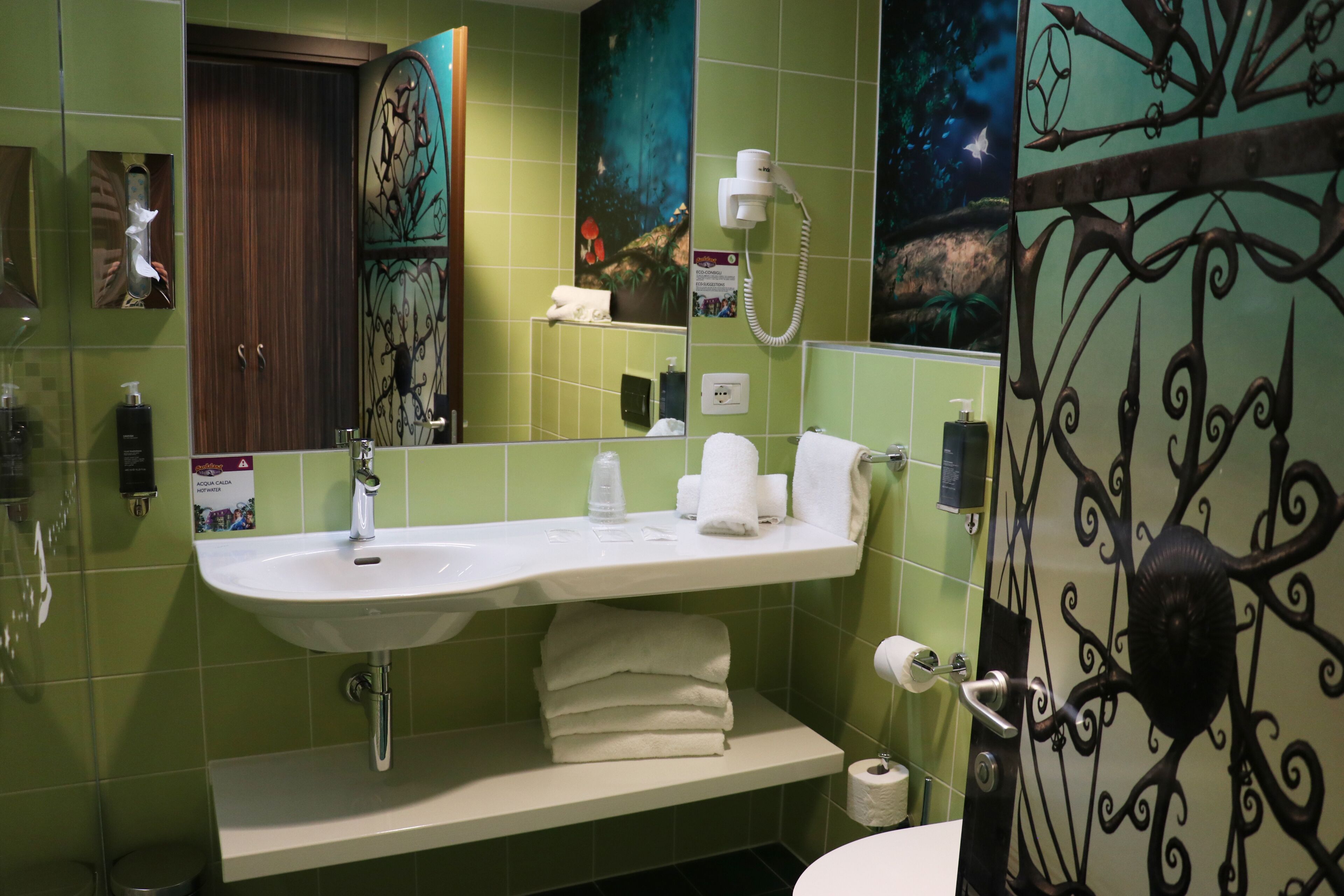 Un baño con lavamanos, espejo, toallero y retrete.