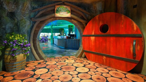 A rustic interior with a wooden barrel door, a sign for 'Querencia Mexican Coffee Bar', and a wooden floor with circular patterns.