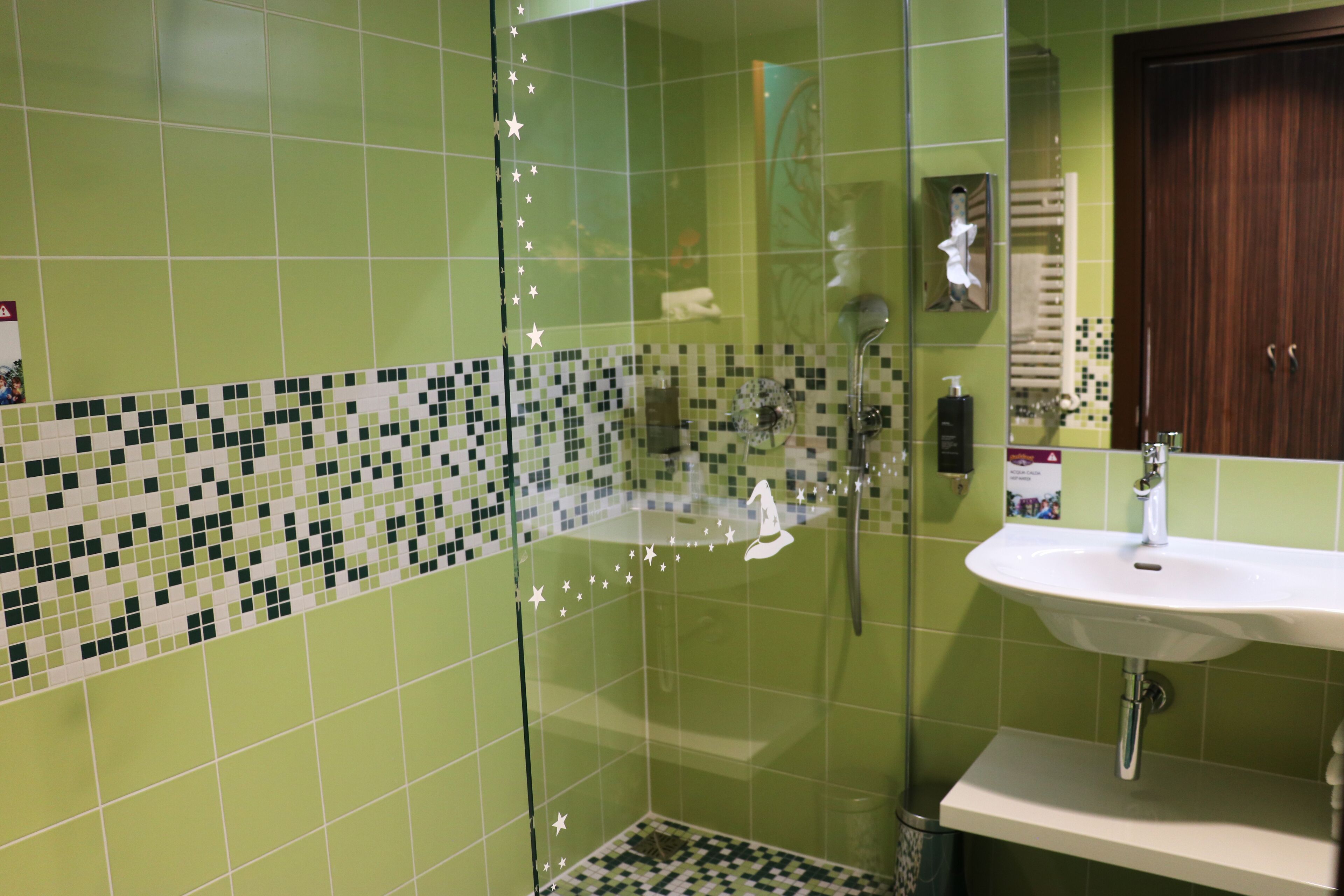 A bathroom with a glass shower enclosure, a sink, and a mirror.
