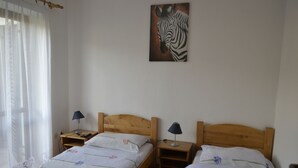 A bedroom with two wooden beds, each with a nightstand and lamp. A zebra painting is on the wall. - Kmecki Hram (Idrija)