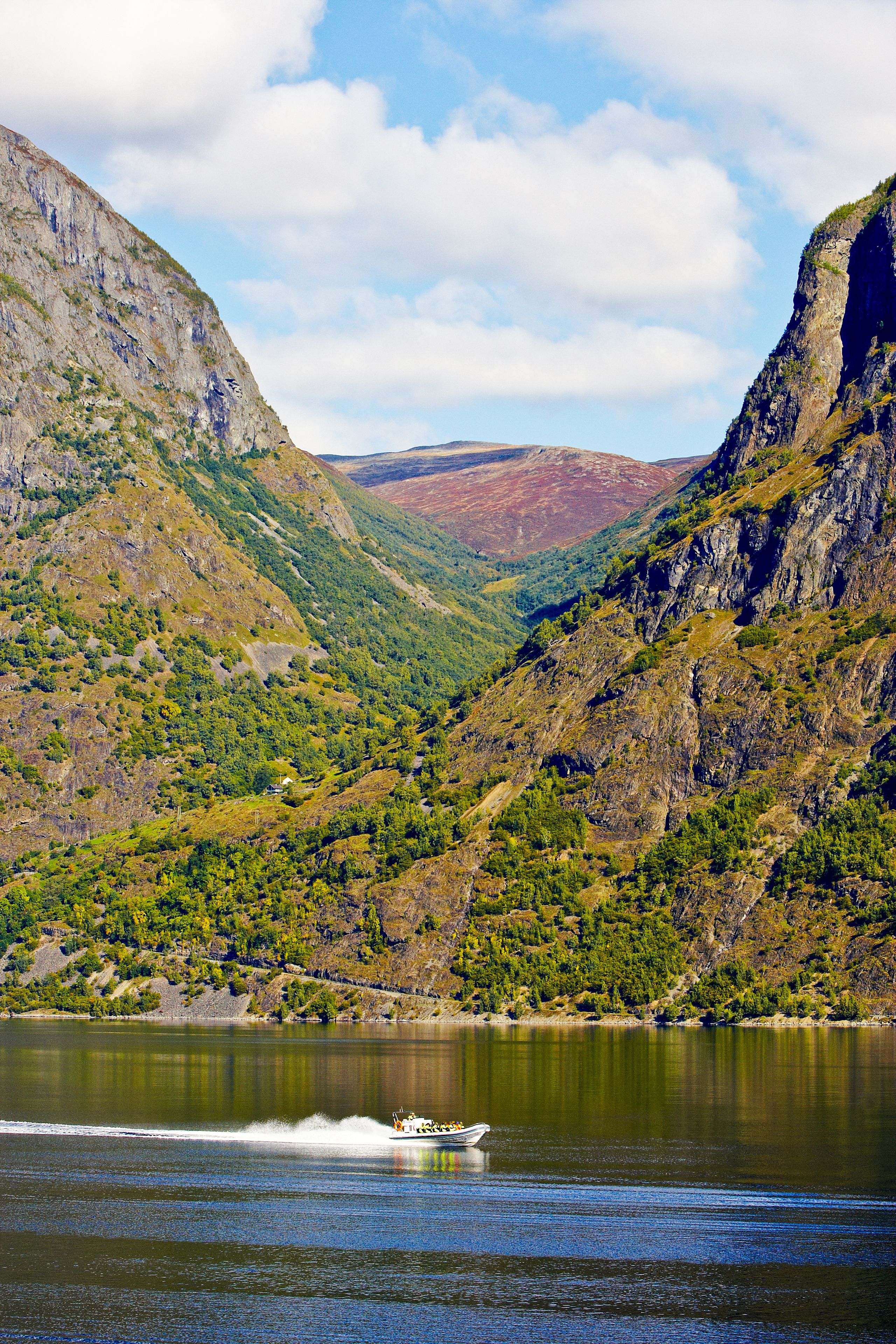 A boat on a calm lake surrounded by rugged mountains.