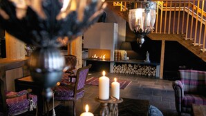 A cozy living room with a fireplace, wooden staircase, and comfortable seating. - Fretheim Hotel (Aurland)