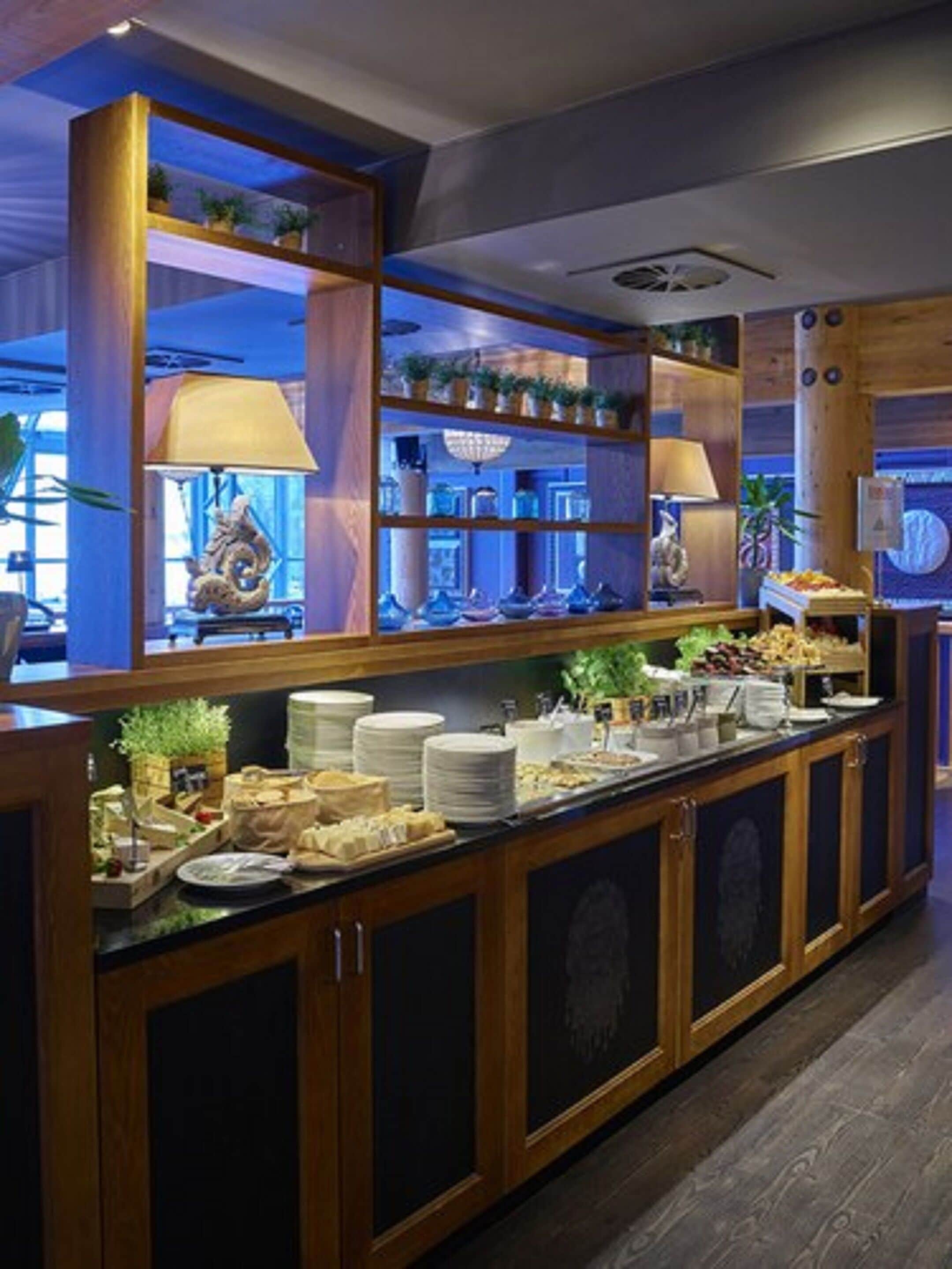 Un buffet avec plusieurs points de service, des étagères ornées d’objets décoratifs et une grande variété de plats et de boissons.