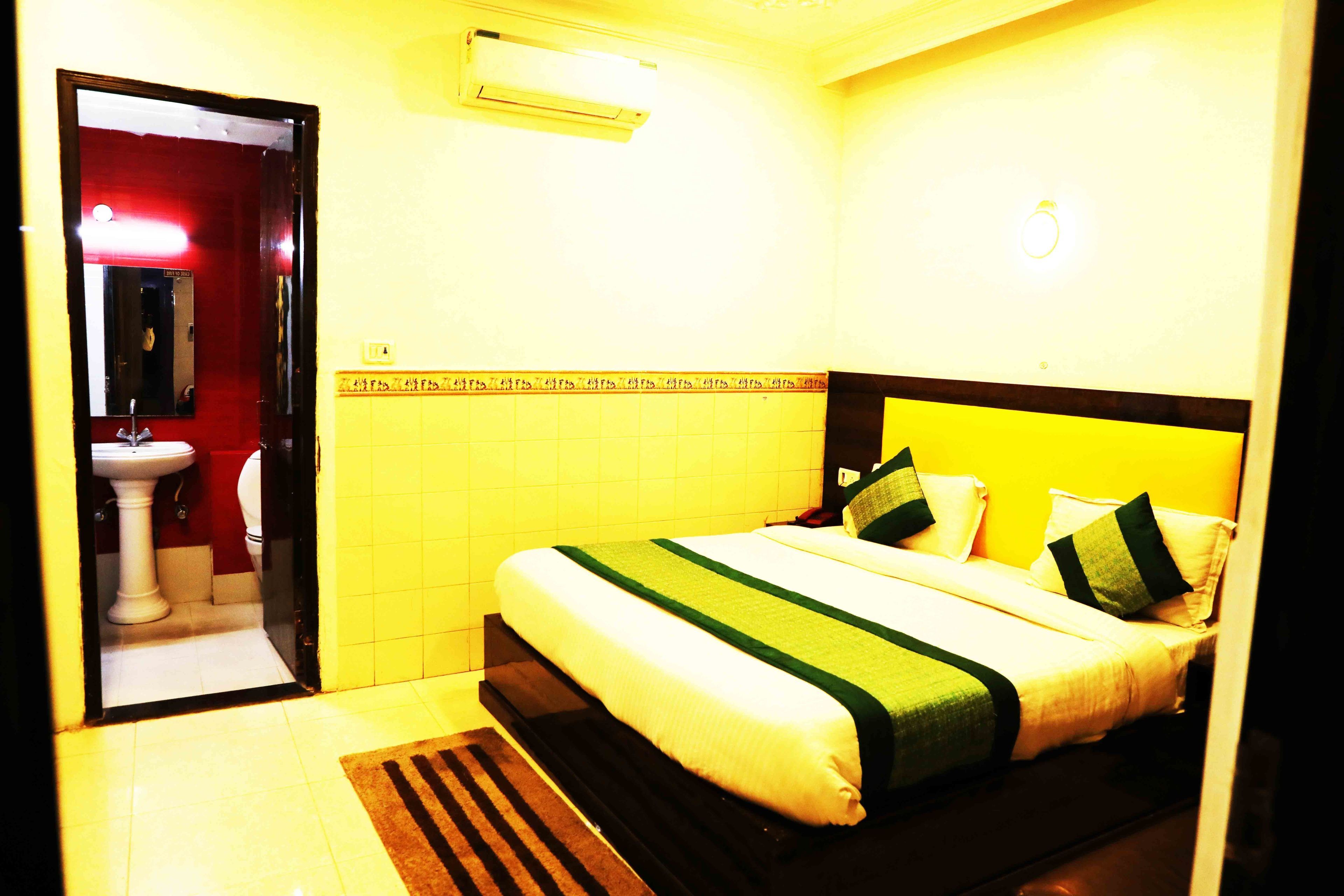 Una habitación de hotel con una cama, baño y espejo.