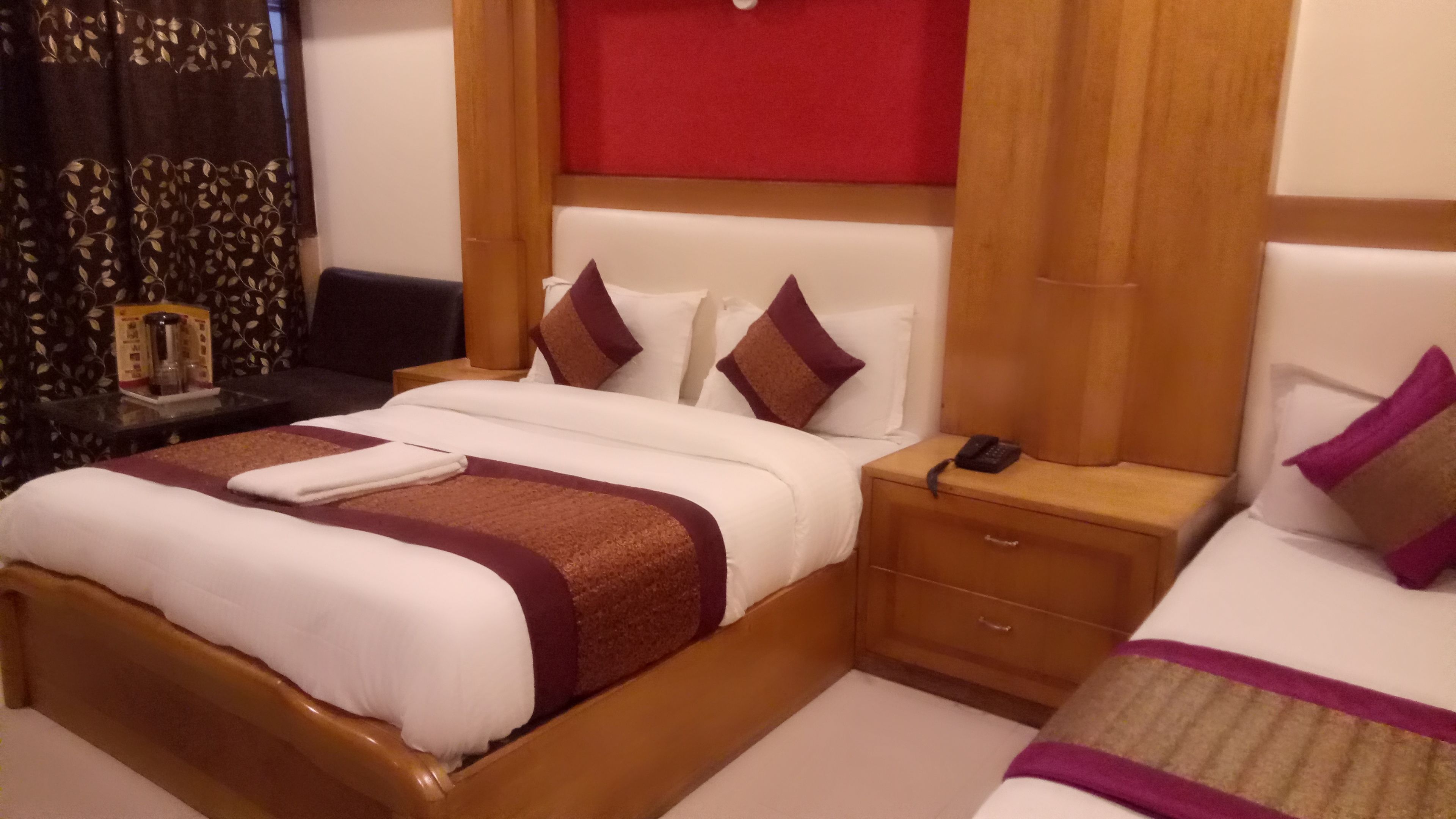 Una habitación de hotel con una cama grande, una mesita de noche y un pequeño escritorio.
