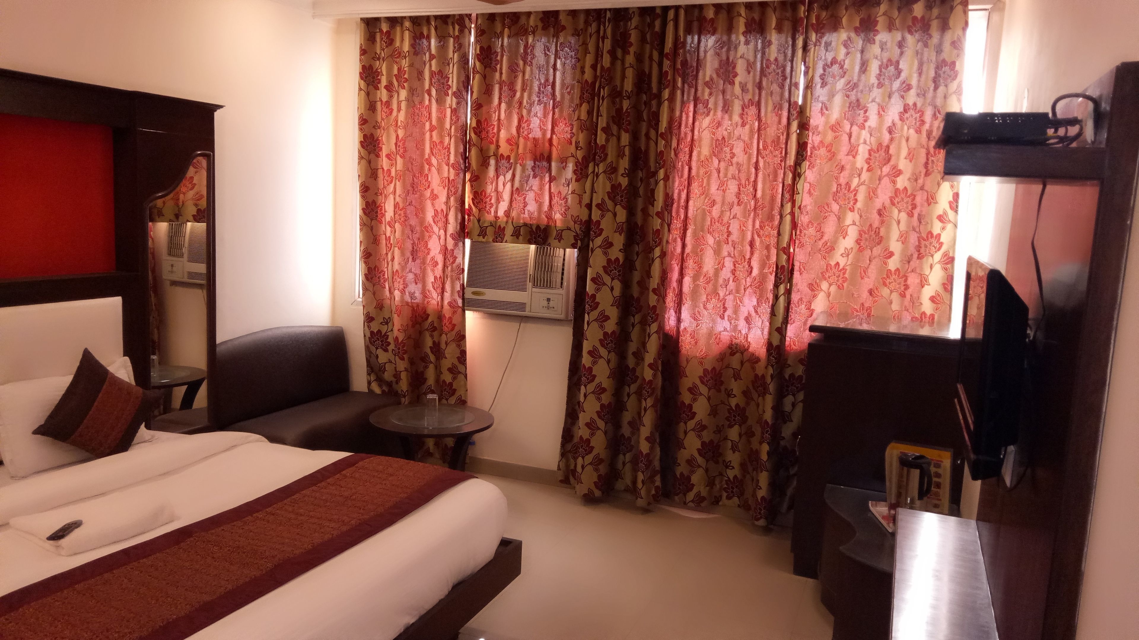 Ein Hotelzimmer mit Bett, Schreibtisch, Sessel, kleinem Tisch und Fernseher.