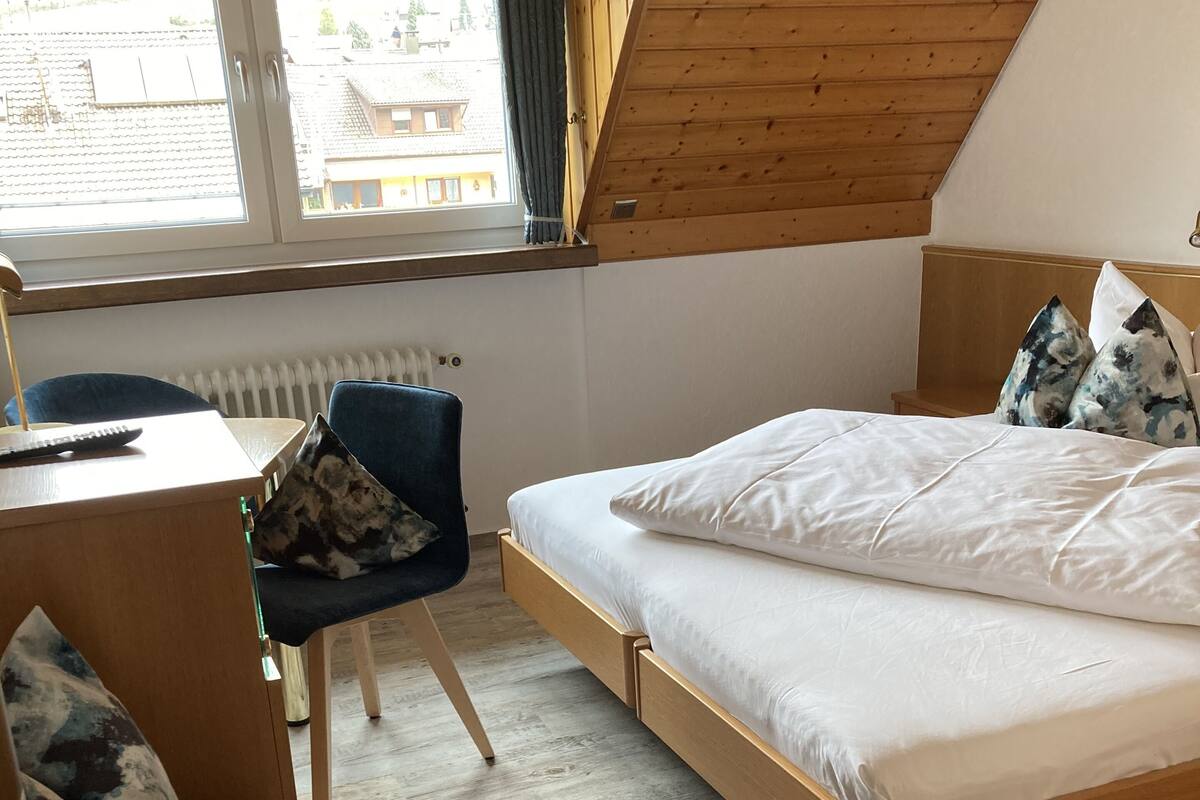 A bedroom with a wooden bed, a desk, a chair, and a radiator.
