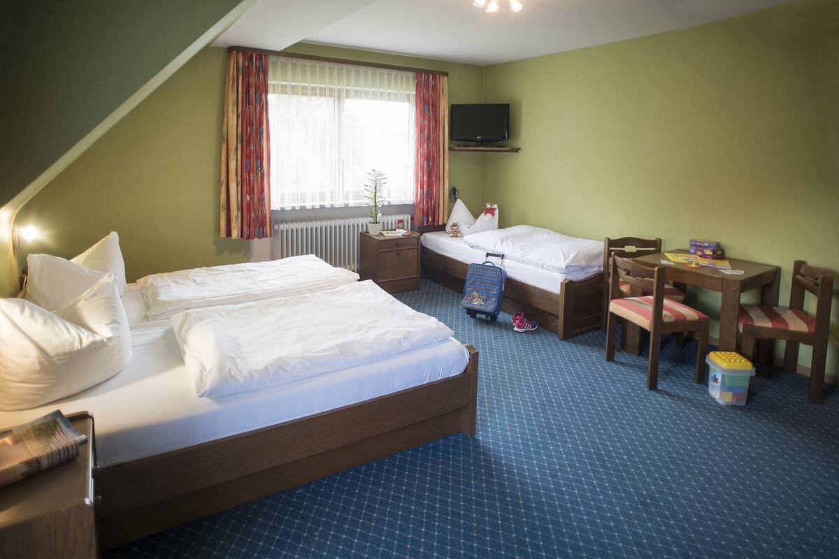 A hotel room with two beds, a desk, and a chair.