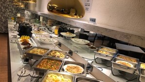 A buffet with various food options, including salads, meats, and other dishes, arranged on a marble countertop. - Surreal Motel- XinJhung Branch (New Taipei City)