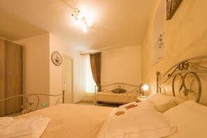 A hotel room with a bed, a bedside table, a lamp, a clock, and a window with curtains. - B&B Seros (Gaeta)