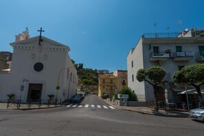 A street with a white church, a yellow building, and a blue building with balconies. - B&B Seros (Gaeta)