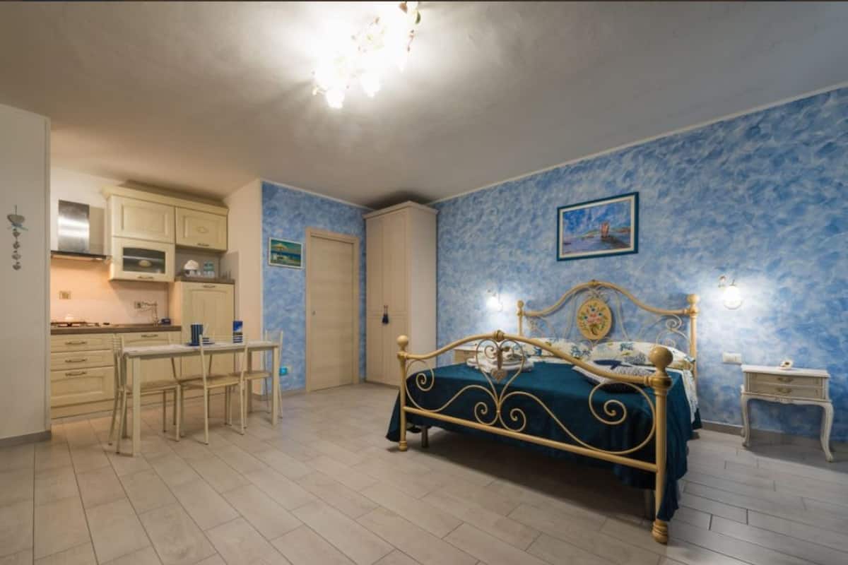 Un dormitorio con cama, mesita de noche, ventana y vistas al exterior.