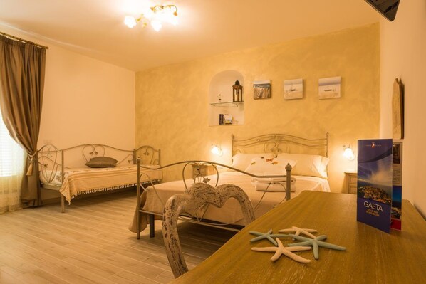 A bedroom with two beds, a wooden table, starfish decoration, and a poster on the wall. - B&B Seros (Gaeta)