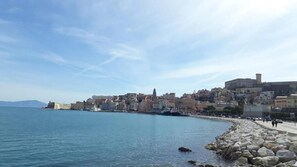 A coastal cityscape with historic buildings along a rocky shoreline. - B&B Seros (Gaeta)