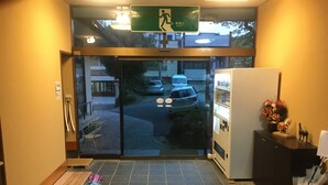 A hotel entrance with a glass door, a sign above indicating an exit, and a parking area visible through the door. - Hotel Kikuya (Kaminoyama)