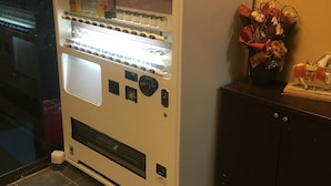 A vending machine with various drinks and snacks, a payment slot, and a small display screen. - Hotel Kikuya (Kaminoyama)