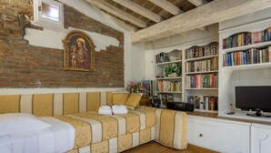 Een gezellige kamer met een bank, een boekenplank vol boeken, een televisie en een decoratief wandobject.
