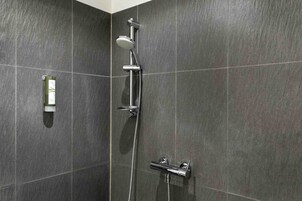 A shower with a handheld showerhead and a wall-mounted faucet.