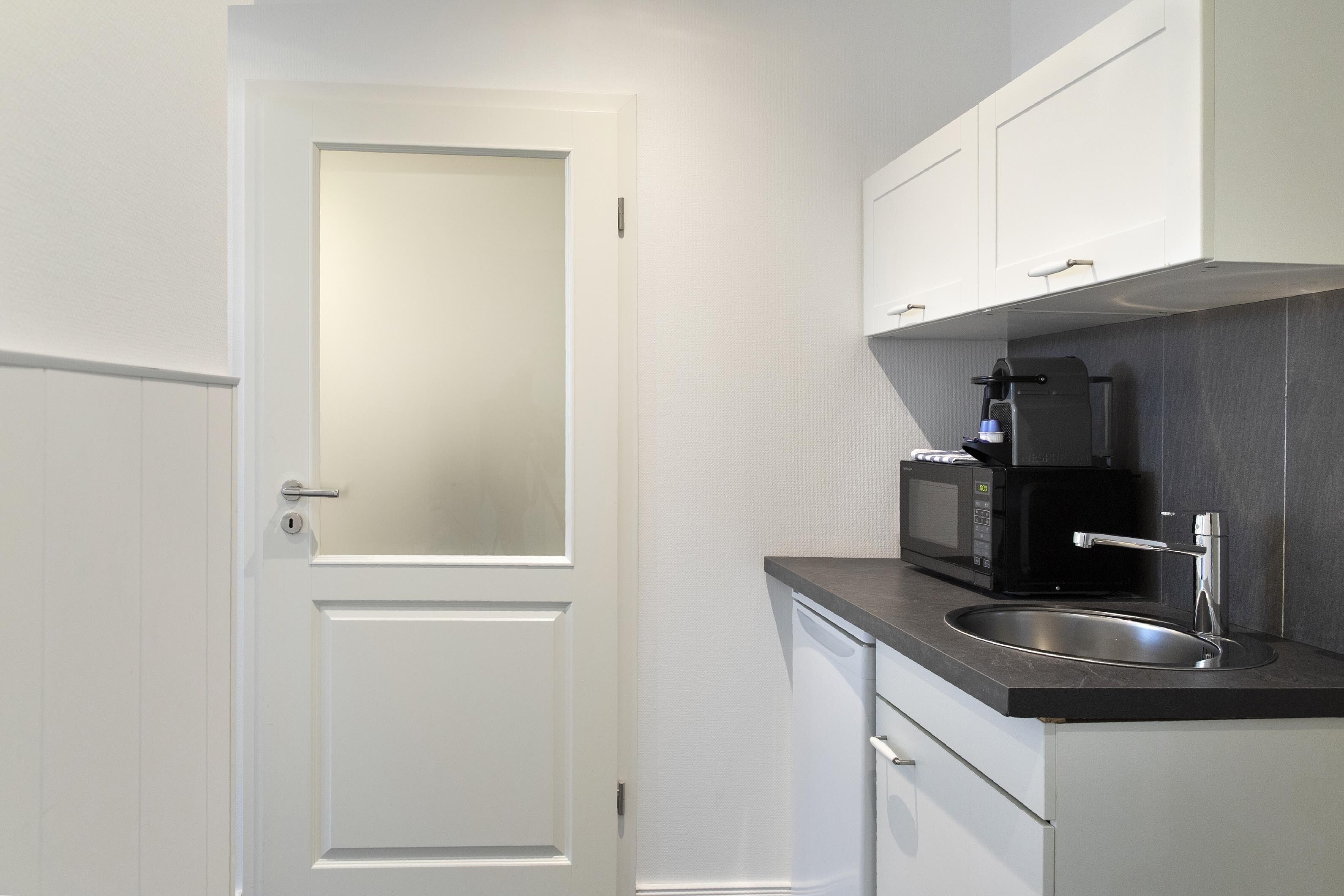 A compact kitchen with a microwave, coffee maker, and a sink.
