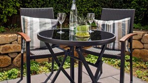 An outdoor seating area with a round table and two chairs, a bottle, and a glass. - Apartment - Boardinghouse on Teuto (Lengerich)