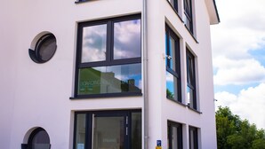 A modern building with a white exterior, multiple windows, and a glass entrance. - Apartment - Boardinghouse on Teuto (Lengerich)