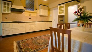 Una cocina con armarios blancos, una estufa y un comedor con mesa y sillas.