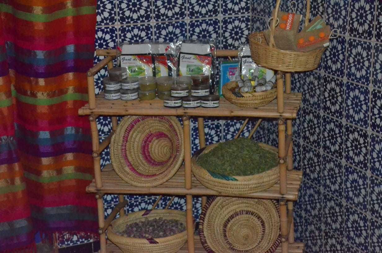 A shelf with jars and baskets, possibly containing food items, against a patterned tile wall.