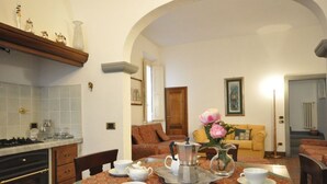 A dining area with a table set for four, a coffee pot, and a vase of flowers. - Ermione (Florence)